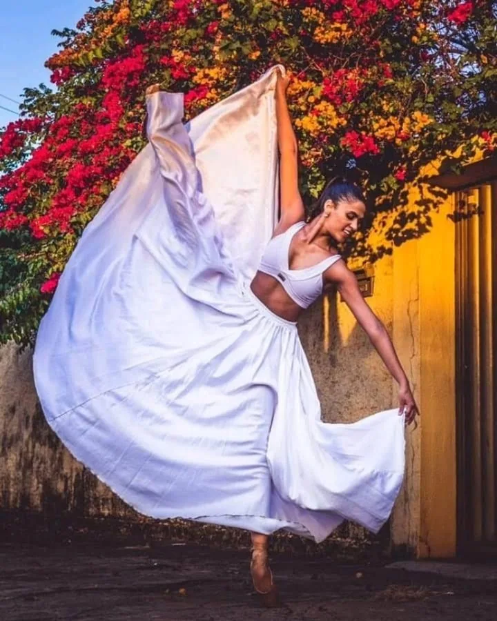 Amanda dançando de vestido branco ao ar livre