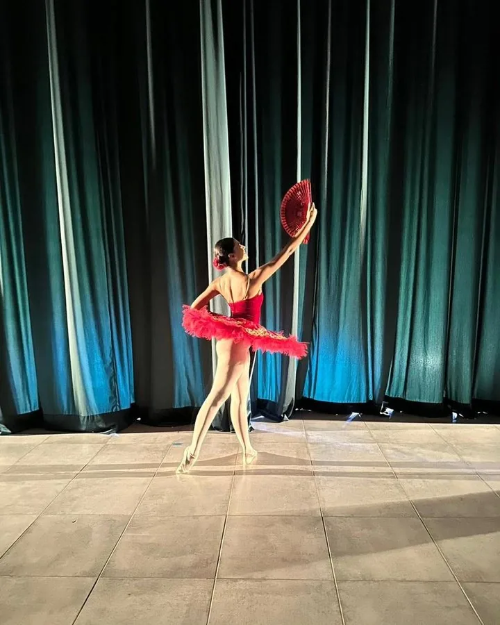 Amanda de tutu vermelho no palco, com leque
