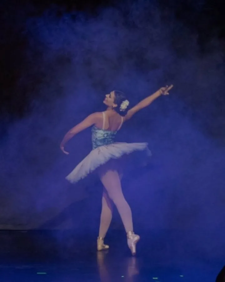 Amanda de tutu no palco, sob luz azul